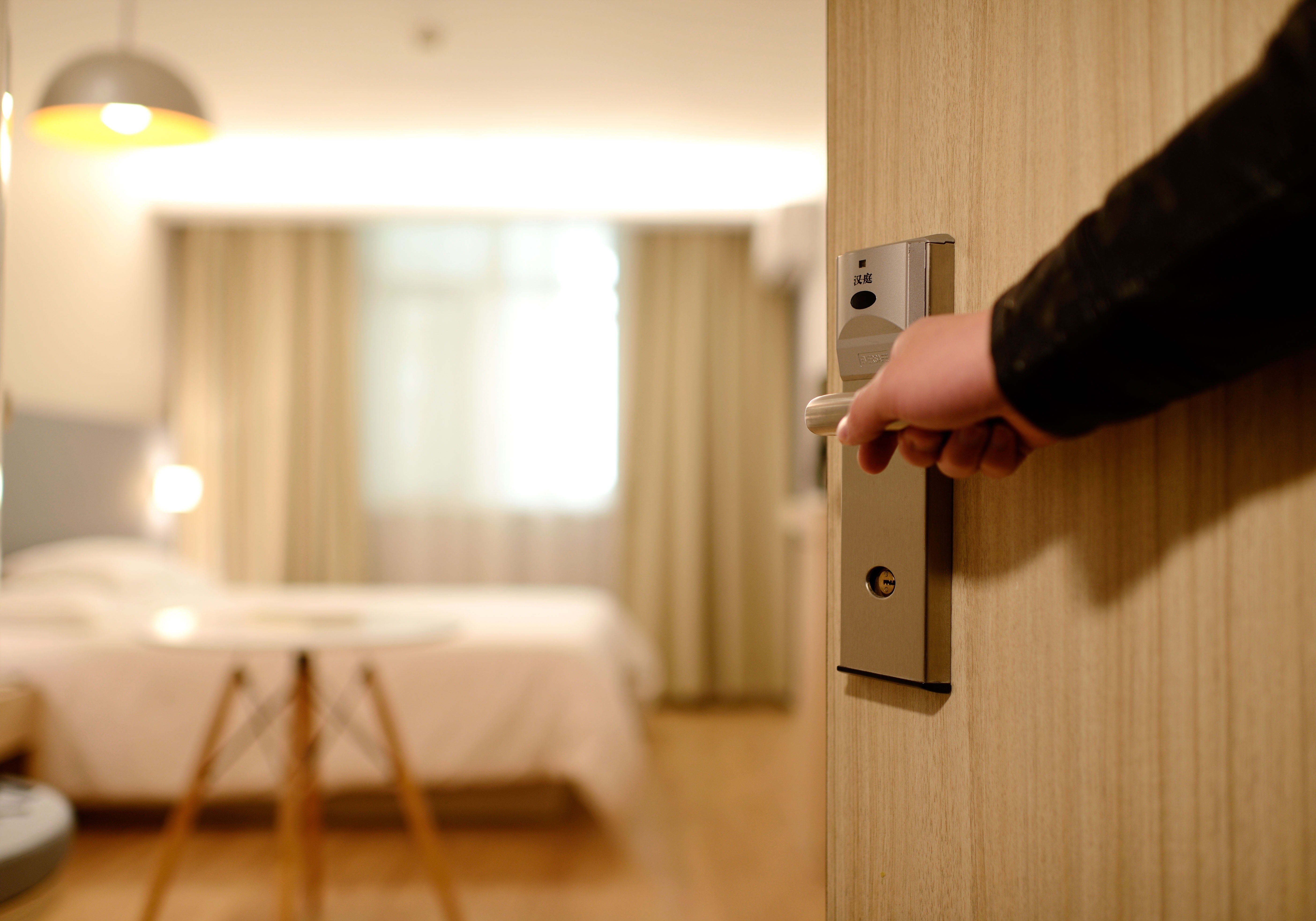 Photo of a person opening a door to a hotel room